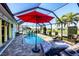 Relaxing screened pool area with outdoor seating and a red umbrella for shade on the brick-paved lanai at 429 Rotonda Cir, Rotonda West, FL 33947