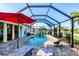 Inviting screened pool with a brick-paved lanai, a red umbrella, and comfortable outdoor seating at 429 Rotonda Cir, Rotonda West, FL 33947