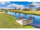 Peaceful canal view with private wooden dock, lush green landscaping, and charming homes in background at 497 Rotonda Cir, Rotonda West, FL 33947