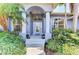 Elegant front entryway with a covered porch, decorative glass door, and lush green landscaping at 52 Marker Rd, Rotonda West, FL 33947