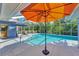 A screened-in pool with an orange umbrella offering shade and clear blue water for relaxation and enjoyment at 52 Marker Rd, Rotonda West, FL 33947