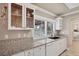 White kitchen with granite countertops, glass-front cabinets, and a window overlooking the backyard at 5292 Early Ter, Port Charlotte, FL 33981