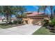 House front view with tan walls, red tile roof, and two-car garage at 5560 Club View Ln, North Port, FL 34287