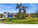 View of coral house with blue garage door and landscaped yard at 62 Marker Rd, Rotonda West, FL 33947