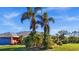 Landscaped front yard with lush tropical plants and palm trees at 62 Marker Rd, Rotonda West, FL 33947