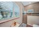 Walk-in shower with glass door, decorative tile, and an arched window for natural lighting at 8 Broadmoor Ln, Rotonda West, FL 33947