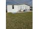 Rear view of a white manufactured home with a satellite dish and AC unit at 8479 Tanaka Dr, Englewood, FL 34224