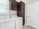 Bright laundry room, featuring dark cabinetry, and modern washer and dryer at 8960 Scallop Way, Placida, FL 33946