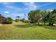 Serene backyard with a vast grassy area and a variety of trees at 910 Park Place Dr, Englewood, FL 34223