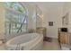 Oval bathtub with large window and built-in vanity at 910 Park Place Dr, Englewood, FL 34223