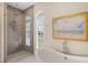 Bright bathroom featuring a soaking tub, walk-in shower, shuttered windows, and stylish decor at 9860 Eagle Preserve Dr, Englewood, FL 34224