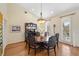 A formal dining room area with a wooden table, chairs, china cabinet, and a chandelier with hardwood flooring at 9860 Eagle Preserve Dr, Englewood, FL 34224