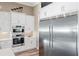 Kitchen with stainless steel refrigerator and wall ovens, complemented by white cabinetry and countertops at 9861 Eagle Preserve Dr, Englewood, FL 34224