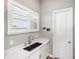 Bright laundry room featuring quartz countertop, black sink, white cabinets, plantation shutters, and decor at 9861 Eagle Preserve Dr, Englewood, FL 34224