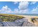 Beach access via boardwalk with stairs leading to the sandy shore under a sunny sky at 1100 Gulf Blvd, Englewood, FL 34223