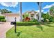 Exterior view of a single-Gathering house with a well manicured lawn and tropical landscaping at 13760 Long Lake Ln, Port Charlotte, FL 33953