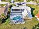 Aerial view showcasing home with solar panels, pool, lush landscaping, and neighborhood at 1443 Quail Lake Dr, Venice, FL 34293