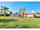 Spacious backyard featuring lush green grass, mature palm trees, and a screened in-ground pool at 1443 Quail Lake Dr, Venice, FL 34293