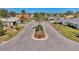 Aerial view of a 'Quail Lake' community entrance with landscaped flower beds, flag, and a well-maintained street at 1443 Quail Lake Dr, Venice, FL 34293