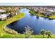 Picturesque aerial view of a serene lake surrounded by lush green grass and houses in the background at 1443 Quail Lake Dr, Venice, FL 34293