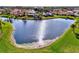 Picturesque aerial view of a serene lake surrounded by lush green grass and houses in the background at 1443 Quail Lake Dr, Venice, FL 34293