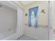 White bathtub, shower with blue curtain, and a window with blue curtains at 1521 Saint Clair Rd, Englewood, FL 34223