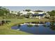 Scenic view of the clubhouse, featuring a pond, palm trees, and a golf course at 232 Southampton Ln # 259, Venice, FL 34293