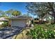 Charming single-story home featuring a two-car garage and a beautifully landscaped front yard with mature trees and flowering plants at 232 Southampton Ln # 259, Venice, FL 34293