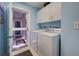 Light blue laundry room with white cabinetry and included washer and dryer at 232 Southampton Ln # 259, Venice, FL 34293