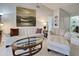 Inviting living room with white sofa and loveseat, a glass-top coffee table, and views into the bathroom at 232 Southampton Ln # 259, Venice, FL 34293