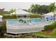 Elevated view of the pool, showcasing the surrounding deck, lounge chairs, palm trees, and lush green foliage at 232 Southampton Ln # 259, Venice, FL 34293