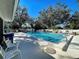 Outdoor pool with clear blue water, surrounded by chairs and mature trees, under a bright blue sky at 232 Southampton Ln # 259, Venice, FL 34293