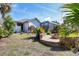 Exterior view of a landscaped backyard with a fire pit, lush plants, and a screened-in pool at 235 Capstan Dr, Placida, FL 33946