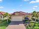 Tan house with a red tile roof and a two-car garage at 24269 Spartina Dr, Venice, FL 34293