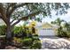 Beautiful yellow house with a white garage door and mature landscaping at 523 Fallbrook Dr, Venice, FL 34292