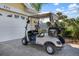 White golf cart parked in the driveway of a yellow house at 523 Fallbrook Dr, Venice, FL 34292