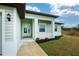 Front entrance with light green siding, white columns, and a welcoming porch at 7186 Rosemont Dr, Englewood, FL 34224