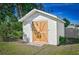 White storage shed with a wooden door in a grassy yard at 7329 Mamouth St, Englewood, FL 34224