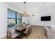 Modern dining room with wood table, light gray chairs, and large windows at 7442 Clearwater St, Englewood, FL 34224