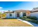 Front view of a single-story home with a brown door and landscaping at 7442 Clearwater St, Englewood, FL 34224