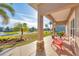 Covered front porch with stone columns, seating area, and view of the landscaped yard at 9240 New Martinsville Ave, Englewood, FL 34224