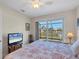 Bright bedroom features a TV, ceiling fan, and sliding glass doors to the screened lanai with water views at 9676 Singer Cir, Port Charlotte, FL 33981