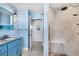 Light and airy bathroom with a walk-in shower featuring white marble tiling and a blue vanity at 1005 E 2Nd St, Englewood, FL 34223