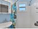 Compact bathroom with a shower/tub combo, white tiling, and vibrant, patterned curtain at 1005 E 2Nd St, Englewood, FL 34223