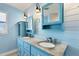 Bright bathroom featuring double sinks, granite counters, and blue cabinetry and shiplap walls at 1005 E 2Nd St, Englewood, FL 34223