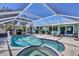 Relaxing view of the pool with built-in spa surrounded by a screen, patio and lush trees at 1005 E 2Nd St, Englewood, FL 34223