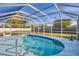 The screened-in pool area features a bright blue deck, a ladder, landscaping, and clear blue skies at 11167 Pendleton Ave, Englewood, FL 34224