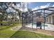 A pleasant backyard featuring a pond and screened-in pool area with a grill at 1216 Whitney Dr, Venice, FL 34293
