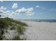 Serene beach scene with soft white sand, clear blue water, and sunbathers enjoying a relaxing day under a sunny, cloudy sky at 1455 New Point Comfort Rd, Englewood, FL 34223