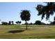 Scenic view of a well-manicured golf course, featuring a sand bunker and palm trees under a clear, bright blue sky at 1455 New Point Comfort Rd, Englewood, FL 34223